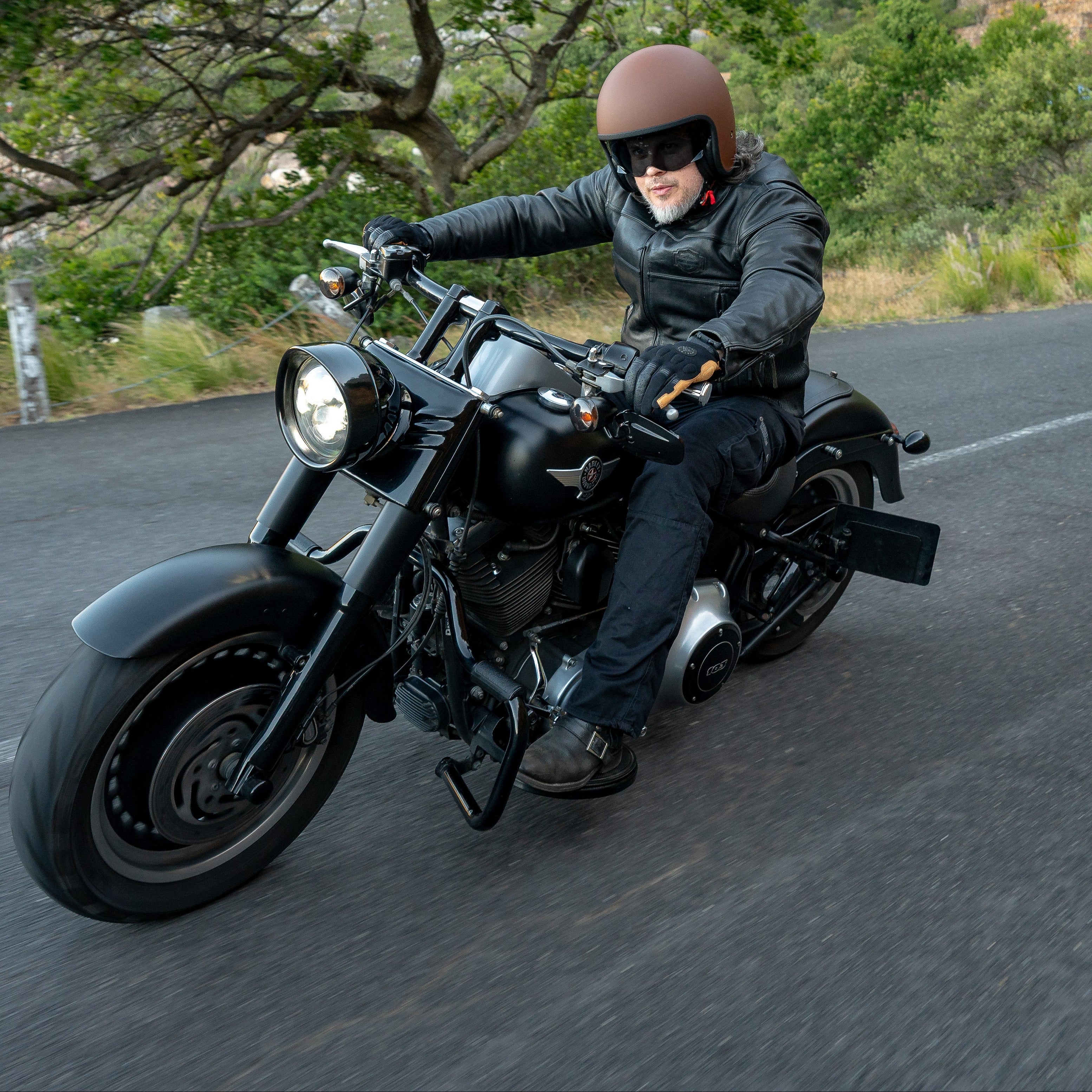 Person riding a motorcycle on a scenic road with greenery